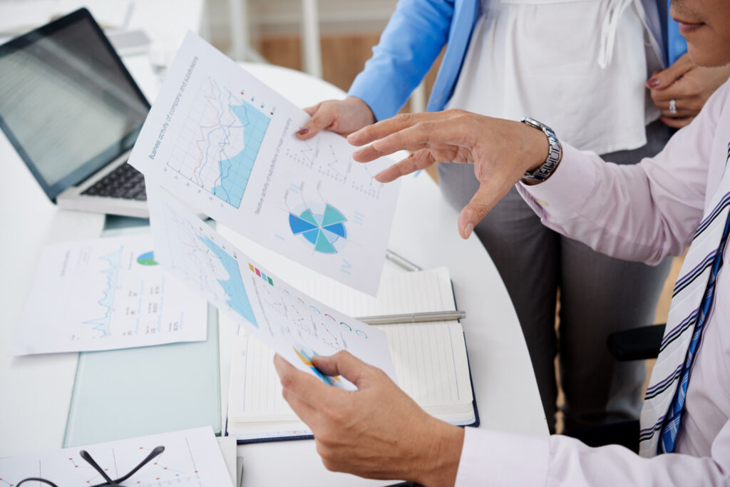 Business professionals reviewing printed charts and graphs at a desk.