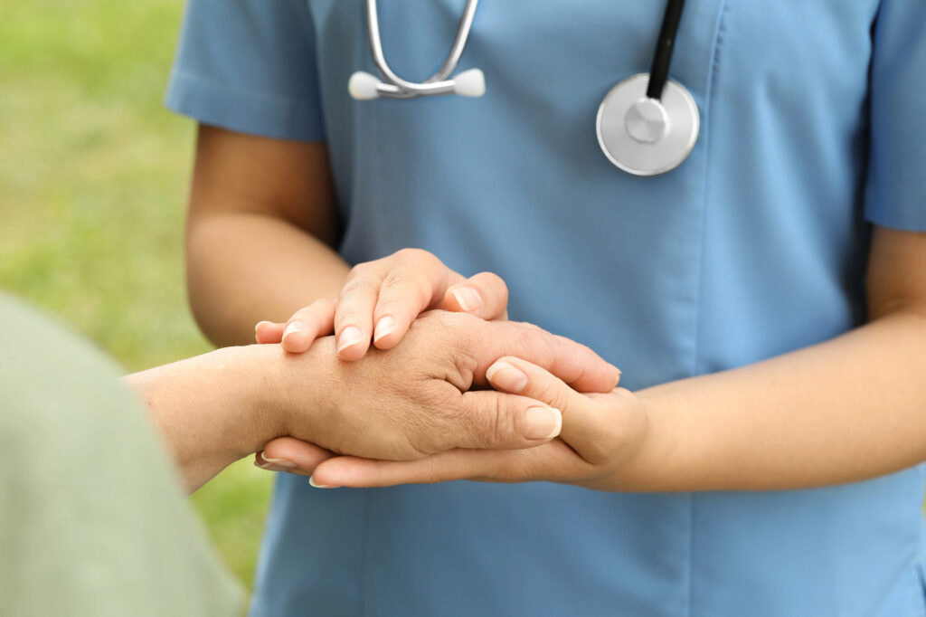 Elderly-woman-and-female-caregiver-holding-hands-closeup